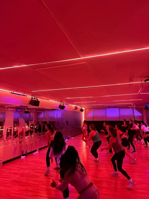A full class dancing under red light in the 305 Fitness Philly studio.